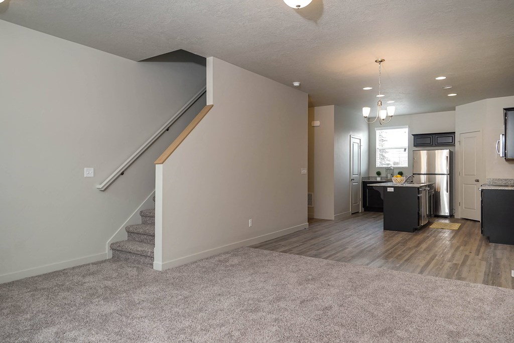 an empty living room with a staircase and a kitchen