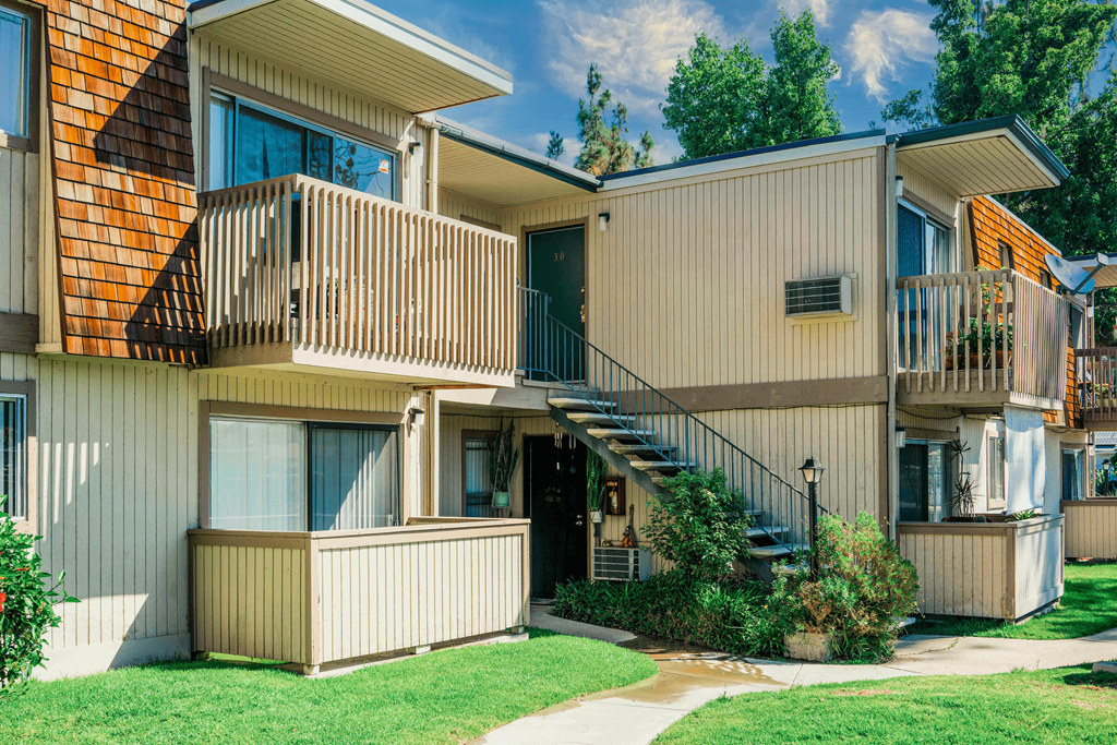 the exterior of a condo building with stairs and a yard