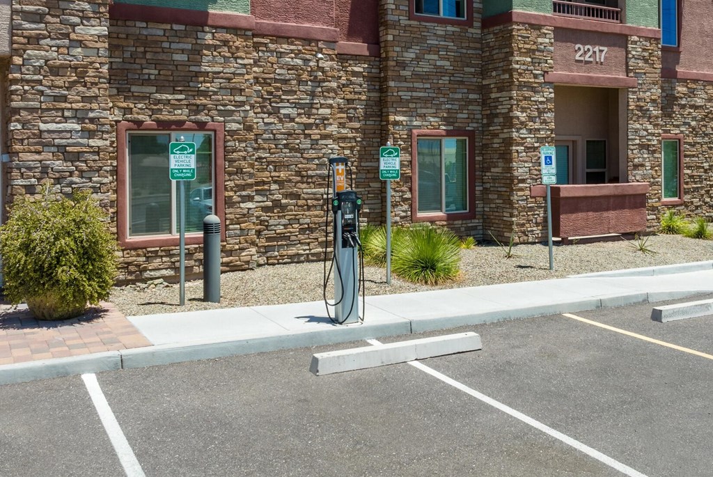 A parking lot with a charging station and a building in the background.