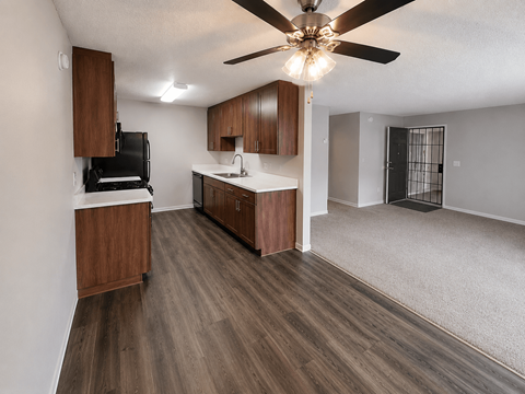 A kitchen with wooden cabinets and a black fridge.