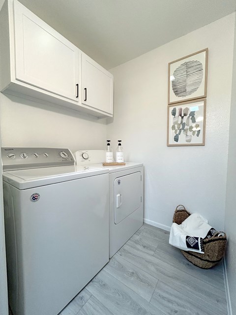 a small laundry room with a washer and dryer and white cabinets