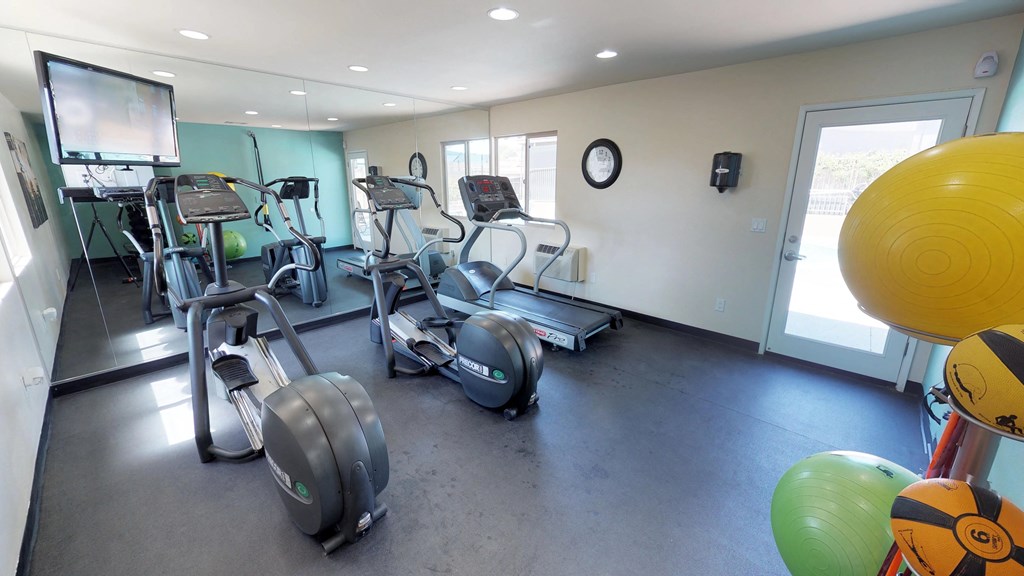 Stationary bikes, treadmill reflected in mirrored wall of fitness center