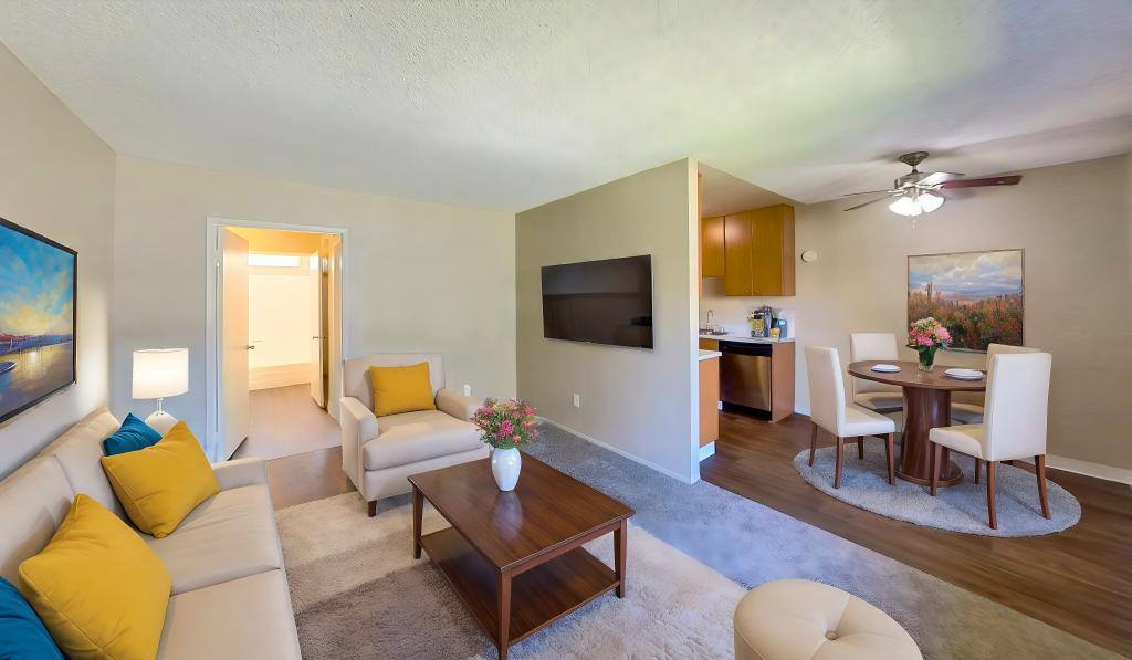 A living room with a couch, chairs, and a television.