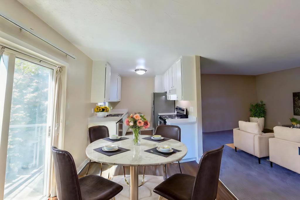 A dining room with a table set for two and chairs around it.