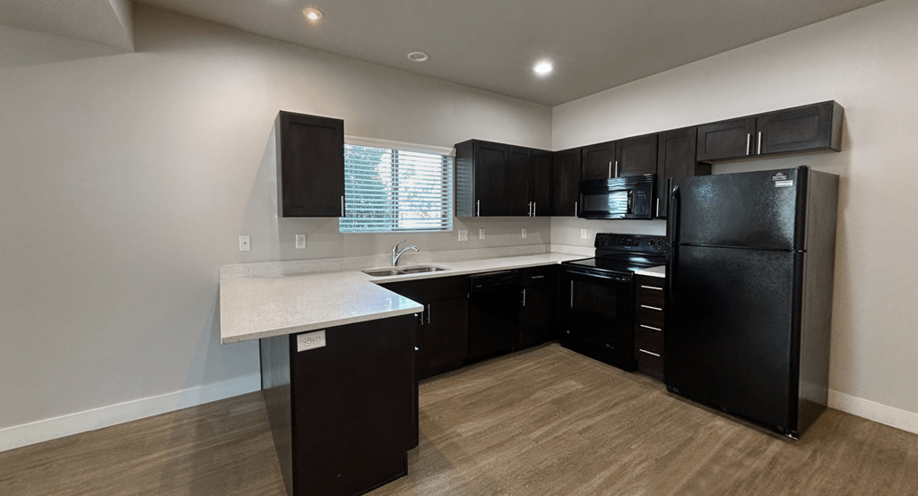 a kitchen with black appliances and white counter tops and dark cabinets