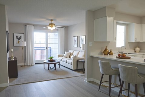 A well-lit living room with a white sofa and a dining table with chairs.