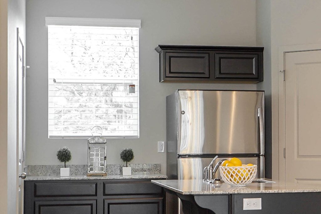 a kitchen with black cabinets and a stainless steel refrigerator