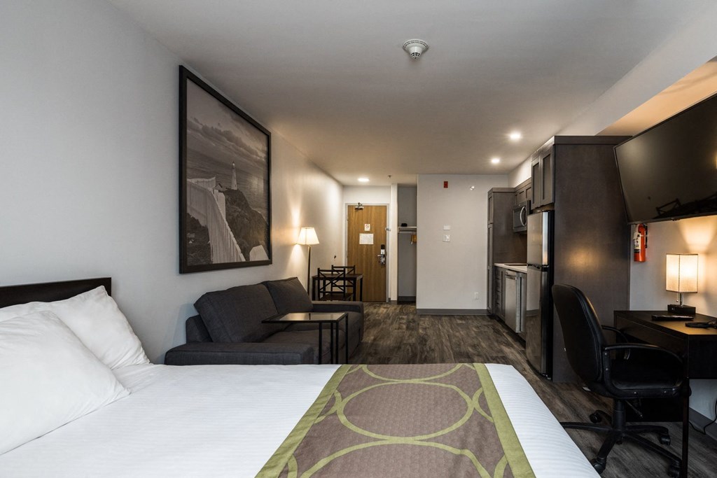 a hotel room with a bed and a couch and a kitchen