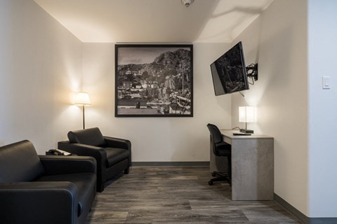 a living room with couches and a desk and a picture on the wall