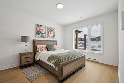 A bedroom with a bed, nightstand, and lamp.