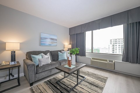 A living room with a grey couch, a coffee table, and a painting on the wall.
