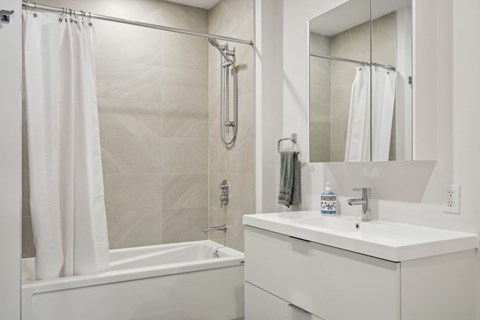 A white bathroom with a tub, sink, and mirror.