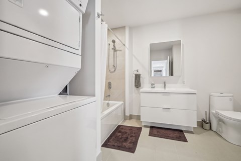 A white bathroom with a brown rug on the floor.