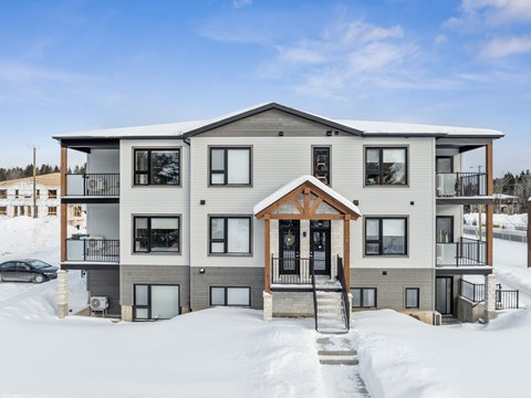 A modern house with a balcony and a snow-covered ground.