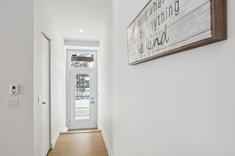 A hallway with a wooden floor and a sign on the wall that says "a good word when nothing else will do".