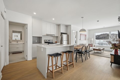 A modern kitchen with a bar stool and a dining table.