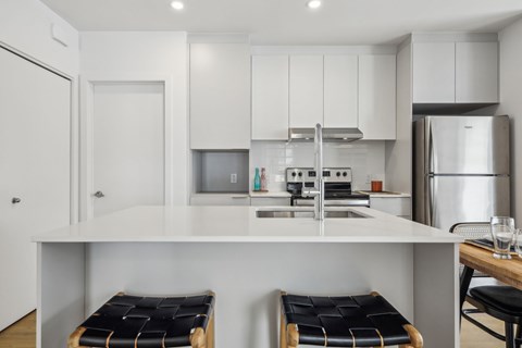 A modern kitchen with white cabinets and a white island.