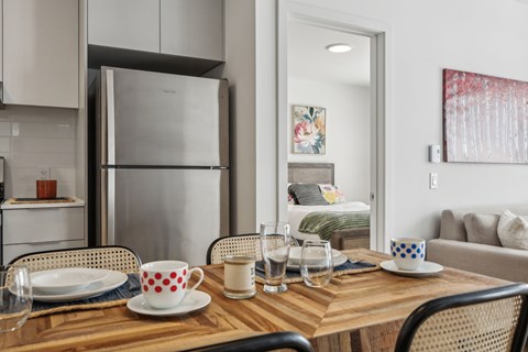 A modern kitchen with a wooden table set for two.