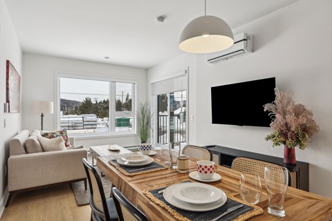 A modern dining room with a wooden table set for two.