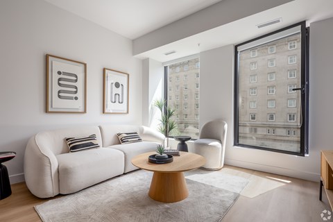 A living room with a white sofa, a wooden coffee table, and two framed pictures on the wall.