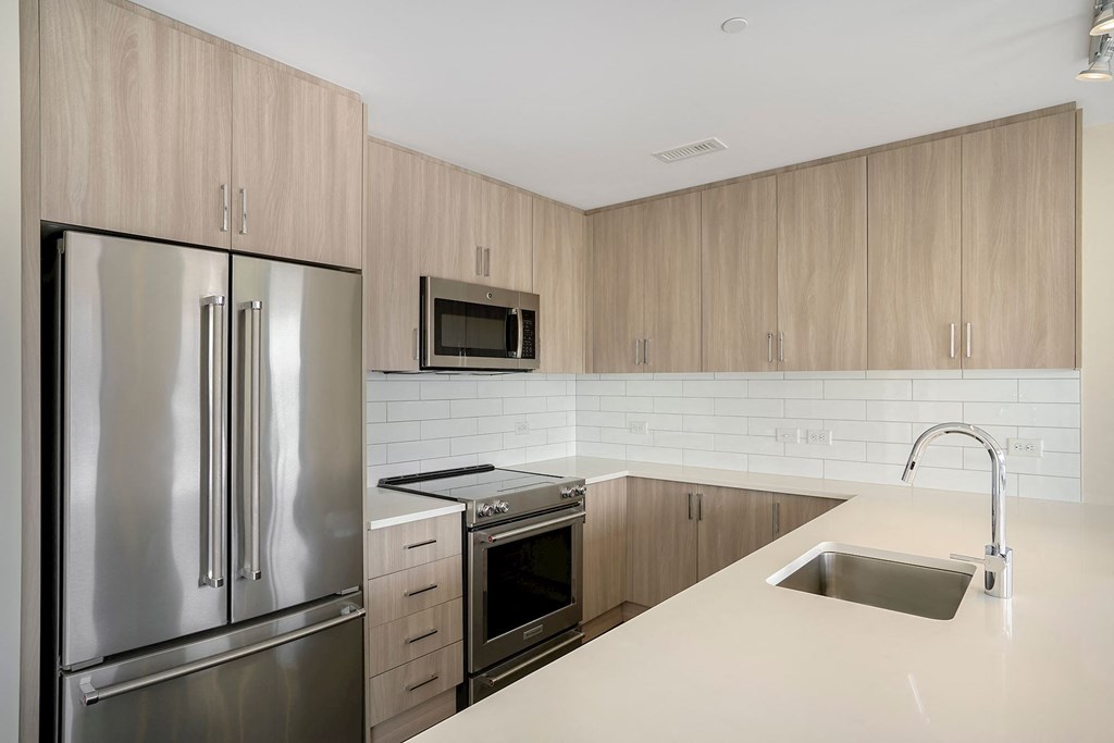 a modern kitchen with stainless steel appliances and white counter tops