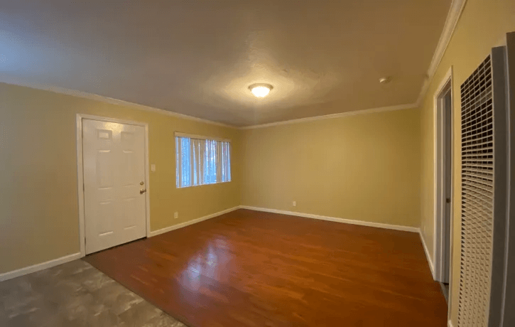 a empty living room with wooden floors and a white door