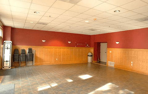 A large room with wooden walls and a clock on the left side.