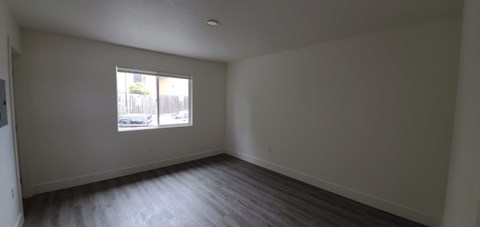 an empty living room with a window and wooden floors