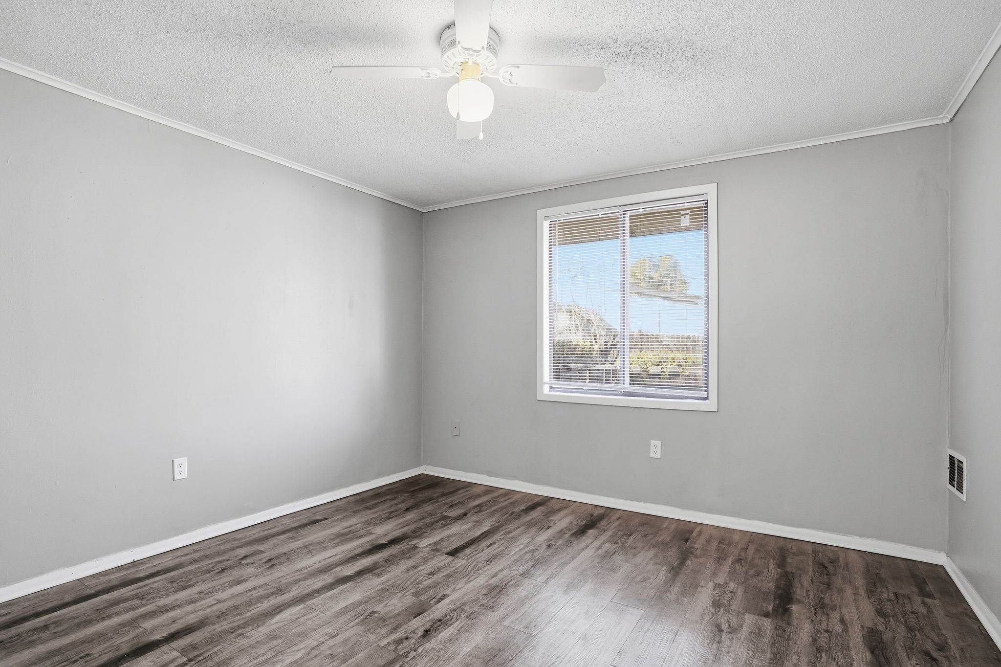 A room with a window and wooden flooring.