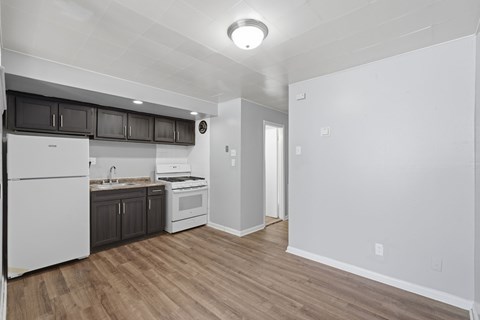 A kitchen with white appliances and wooden floors.