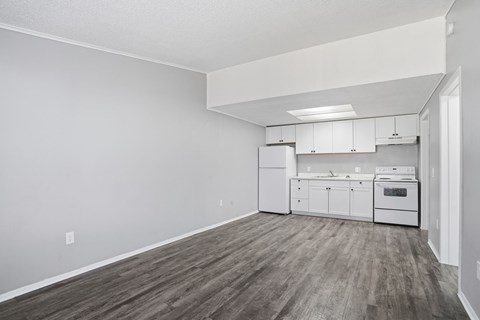A kitchen with white cabinets and a wood floor.