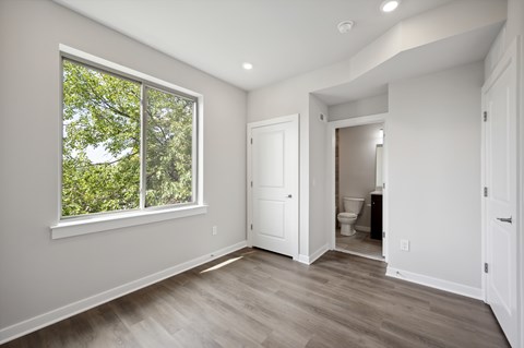 A room with a window and a door leading to a bathroom.