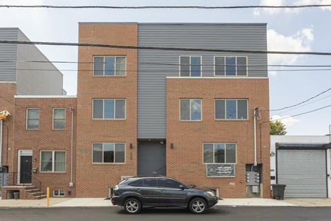 A black car is parked in front of a brick building.