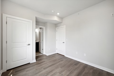 A room with white walls and wooden flooring with two doors.