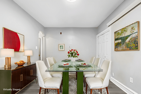 A dining room with a glass table and white chairs.