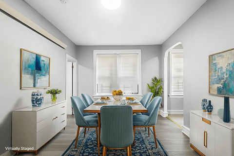 A dining room with a table set for six and a blue rug on the floor.