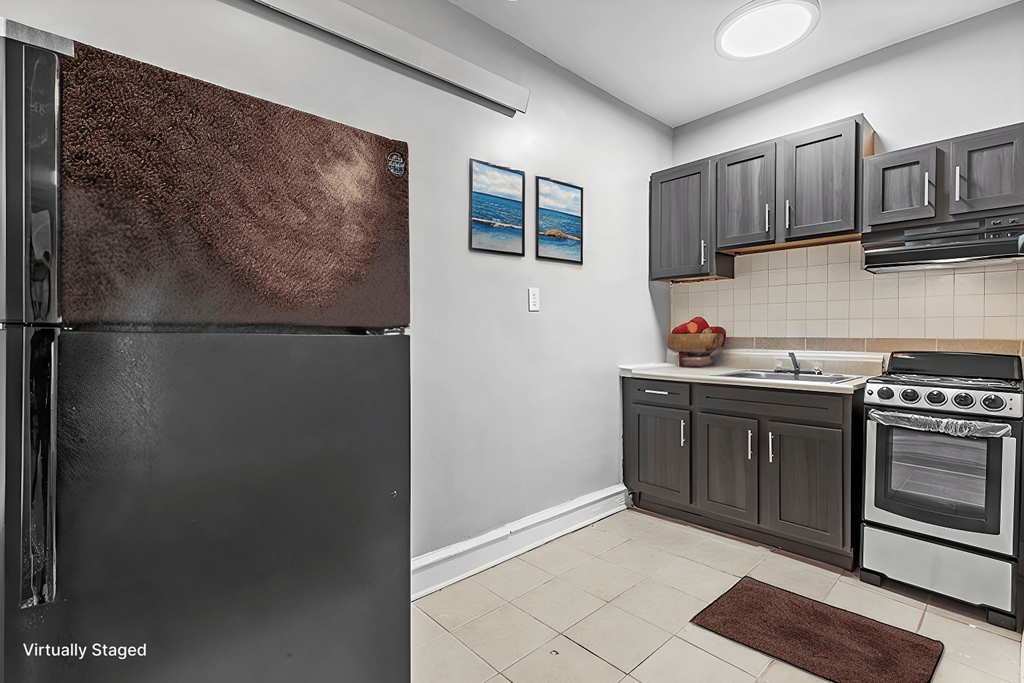 A kitchen with a black refrigerator and a stove top oven.