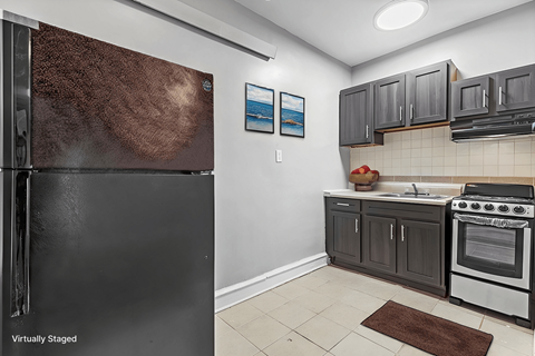 A kitchen with a black refrigerator and a stove top oven.