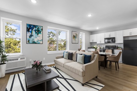 A living room with a beige couch, a coffee table, and a painting on the wall.