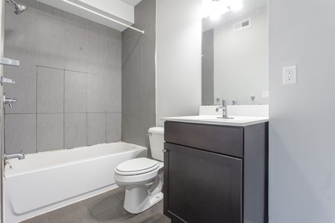 A white toilet sits next to a white bathtub in a bathroom.