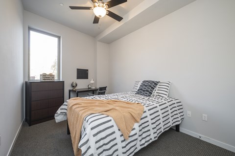 A bedroom with a bed, nightstand, and window.