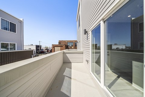 A balcony with a glass railing and a white wall.