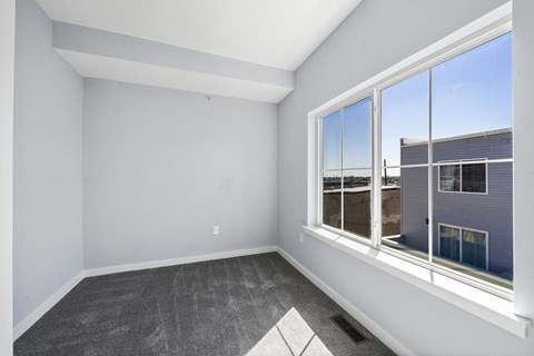 A room with a large window and a grey carpet.