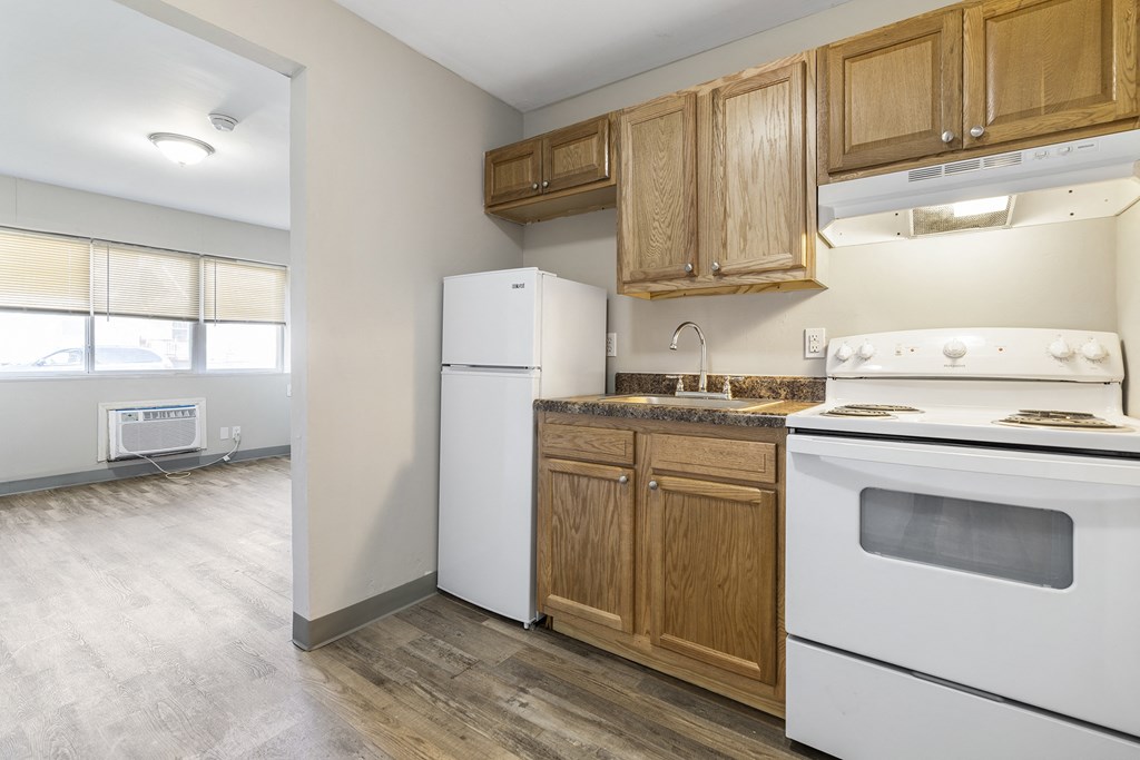 an empty kitchen with white appliances and wooden cabinets