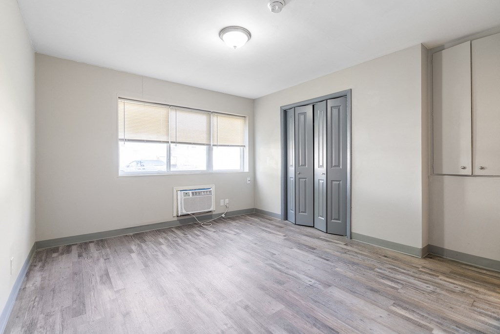 an empty living room with a window and a door to a closet