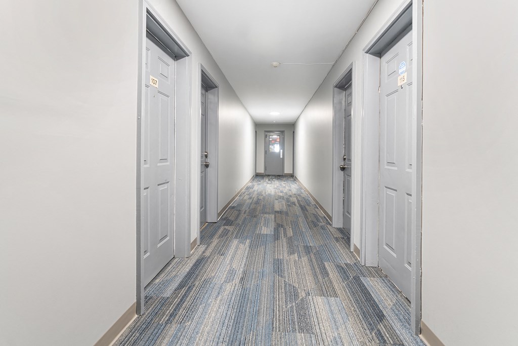 a corridor with white doors and a carpeted floor and white walls