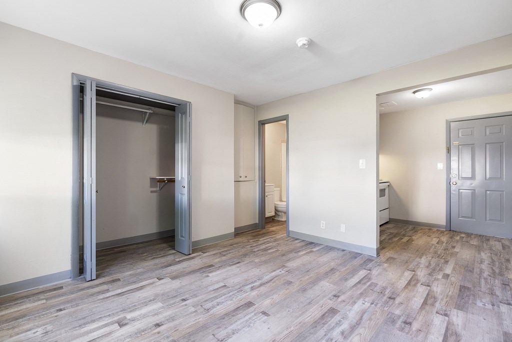 an empty room with a door to a bathroom and a closet