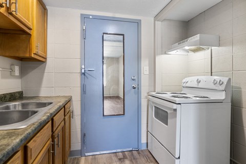 a kitchen with a white stove and a blue door