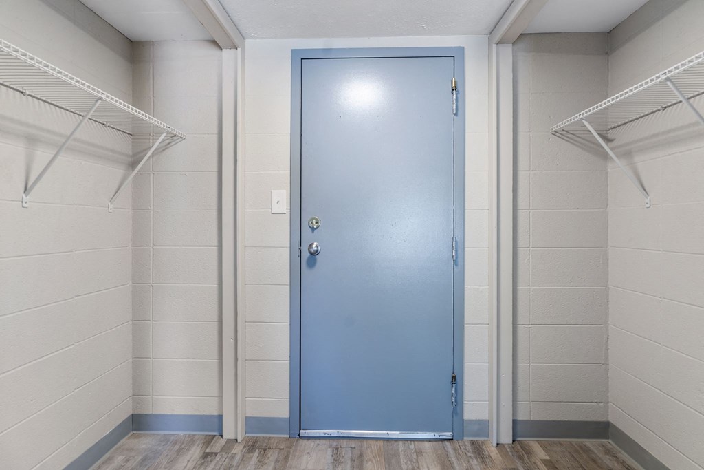 a blue door in the middle of a room with white walls and a wooden floor