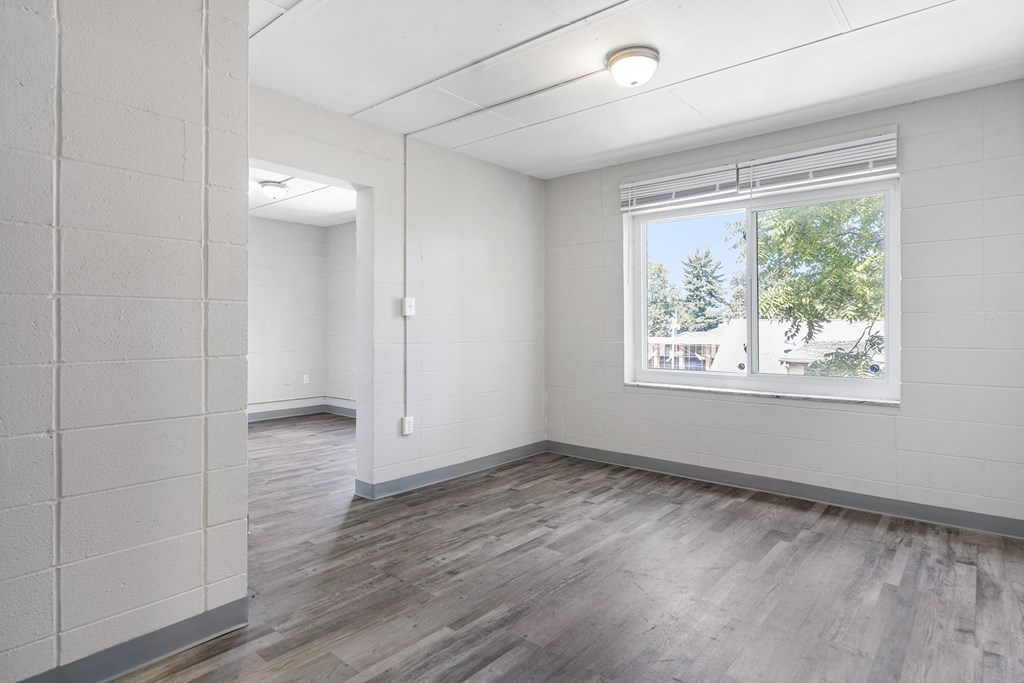 an empty living room with a window and wood flooring